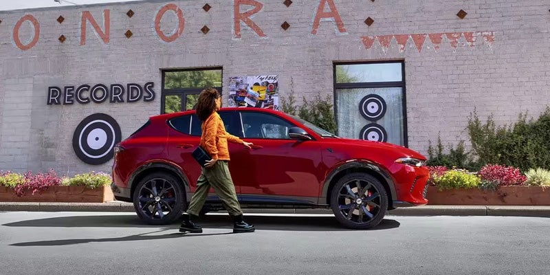 A red SUV parked on a street in front of a building with large murals