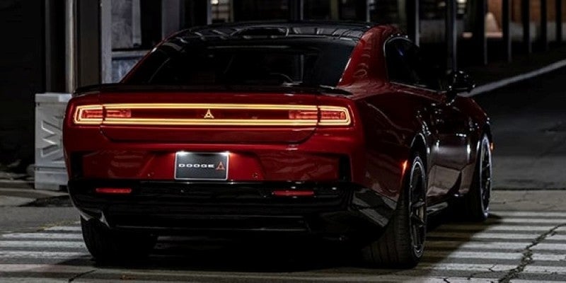 Rear view of a red sports car parked on a dimly lit street at night