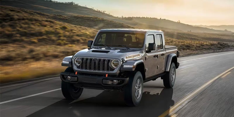 A gray Jeep Gladiator pickup truck driving on a two-lane road
