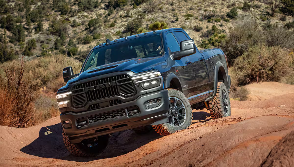 A black RAM heavy-duty pickup truck driving over uneven red rock terrain