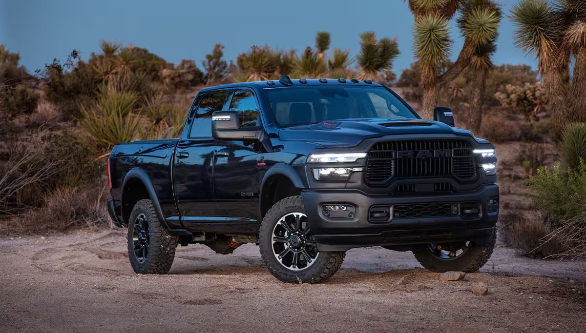 A black RAM heavy-duty pickup truck parked on sandy terrain surrounded by desert plants