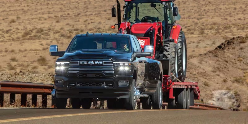 A heavy-duty pickup truck driving on a dirt road through a dry