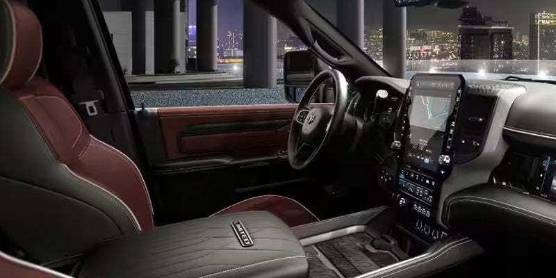 Interior of a RAM vehicle with black and red leather seats, large touchscreen display, and cityscape outside.