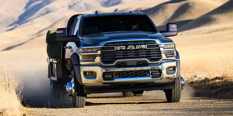 A heavy-duty pickup truck driving on a dirt road through a dry
